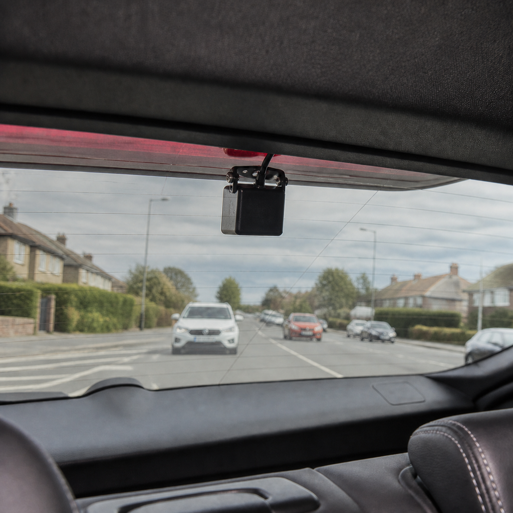 Wired rear camera mounted high-centre with its lens facing out through the rear window